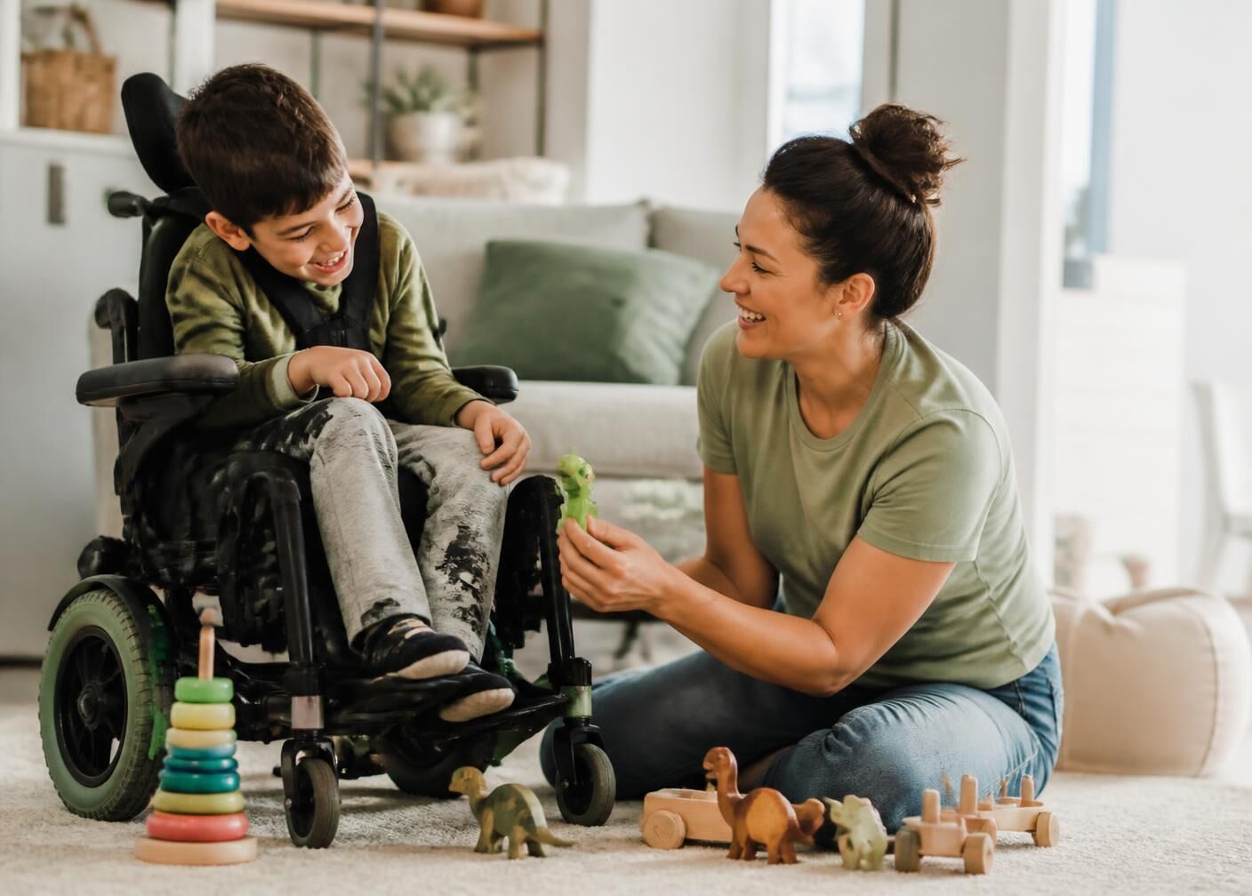 A support professional playing on the floor with a smiling child at home